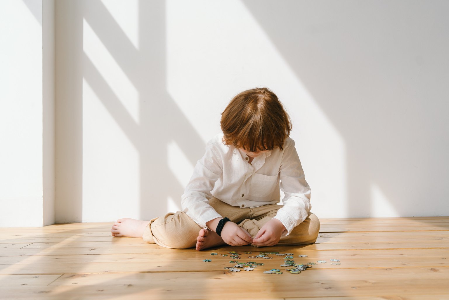 Girl in White Long Sleeve Shirt Playing on Brown Wooden Table